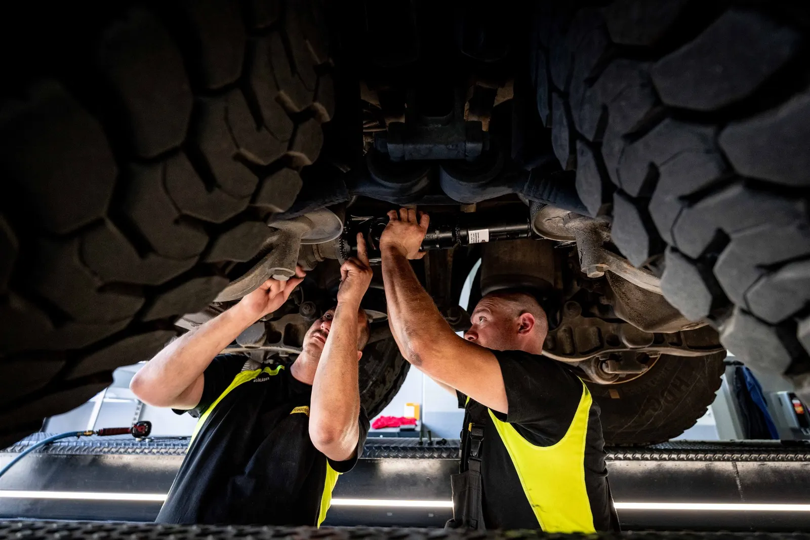 Zwei Mechaniker arbeiten an der Antriebswelle in der Montagegrube